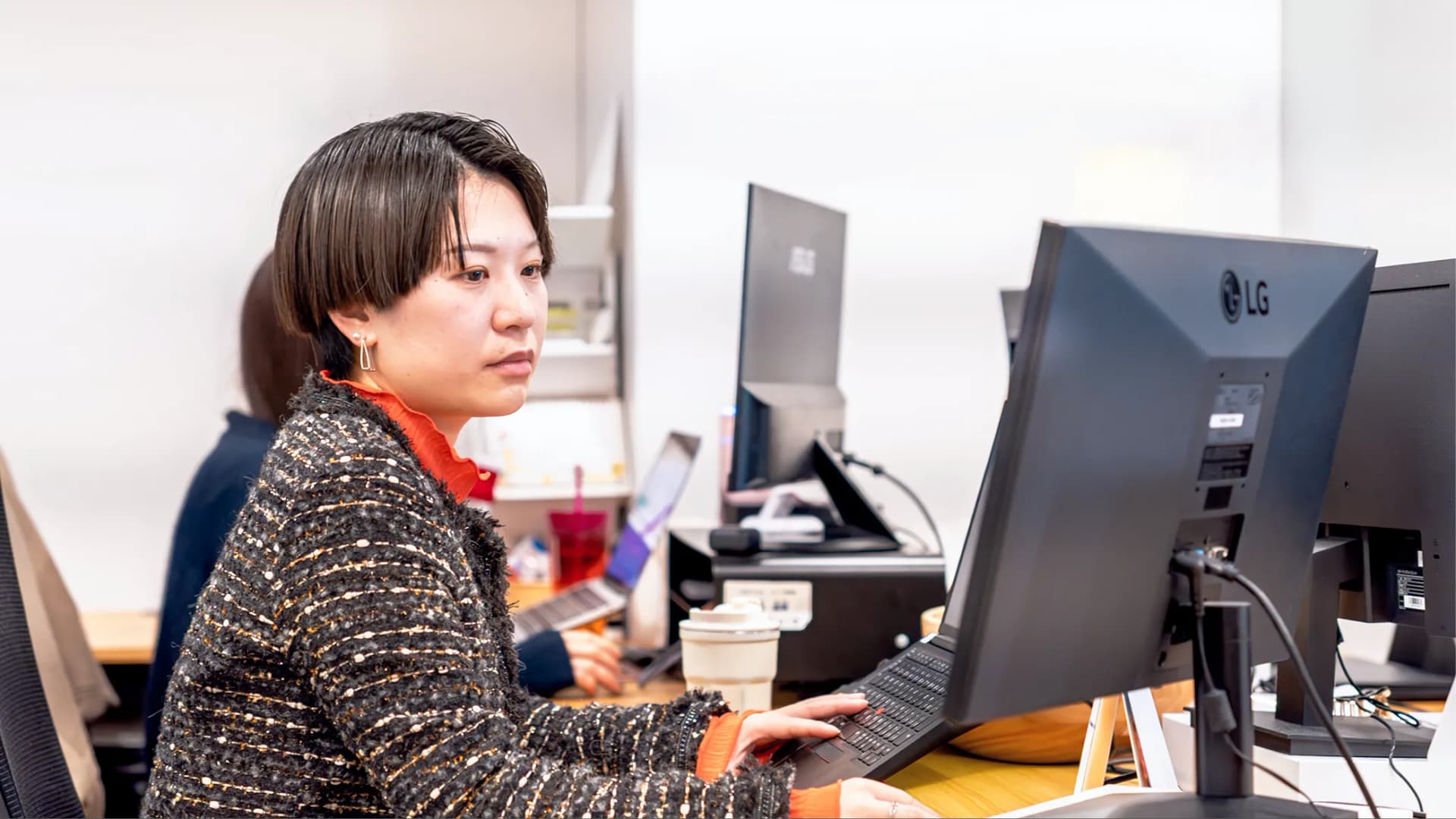 写真。女性がパソコンを操作しながらモニターを見て作業している様子